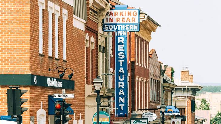 A brick building with a blue sign in the shape of a cross that says "Southern Inn"