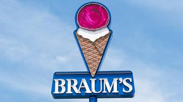 Looking up at a pink ice cream cone sign titled "BRAUM'S" against blue sky