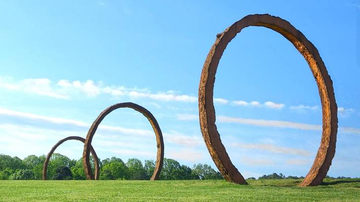 Circle-shaped sculptures on the grass under a blue sky
