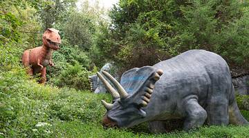 Three dinosaur statues in a green forest area