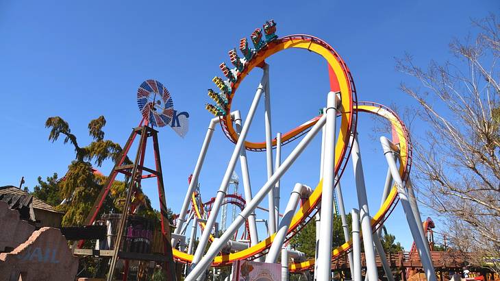 A yellow and red roller coaster in a theme park