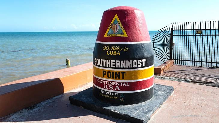 A marker for the Southernmost Point of the US and the ocean in the background A marker for the Southernmost Point of the US and the ocean in the background