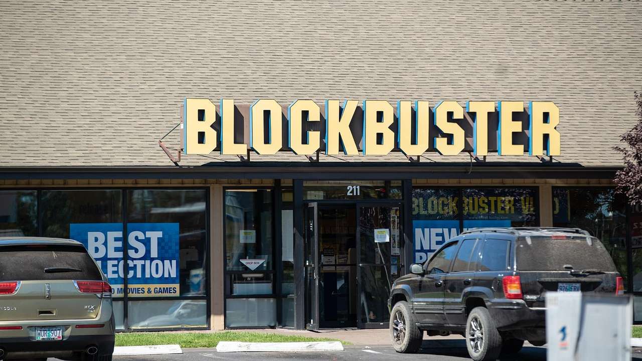 A shop with glass windows and a door with a big yellow sign of "Blockbuster"