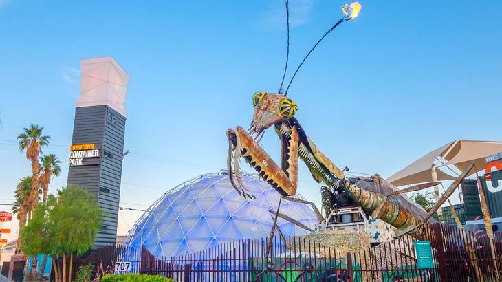 A praying mantis sculpture, dome structure, and tower that says "Container Park"