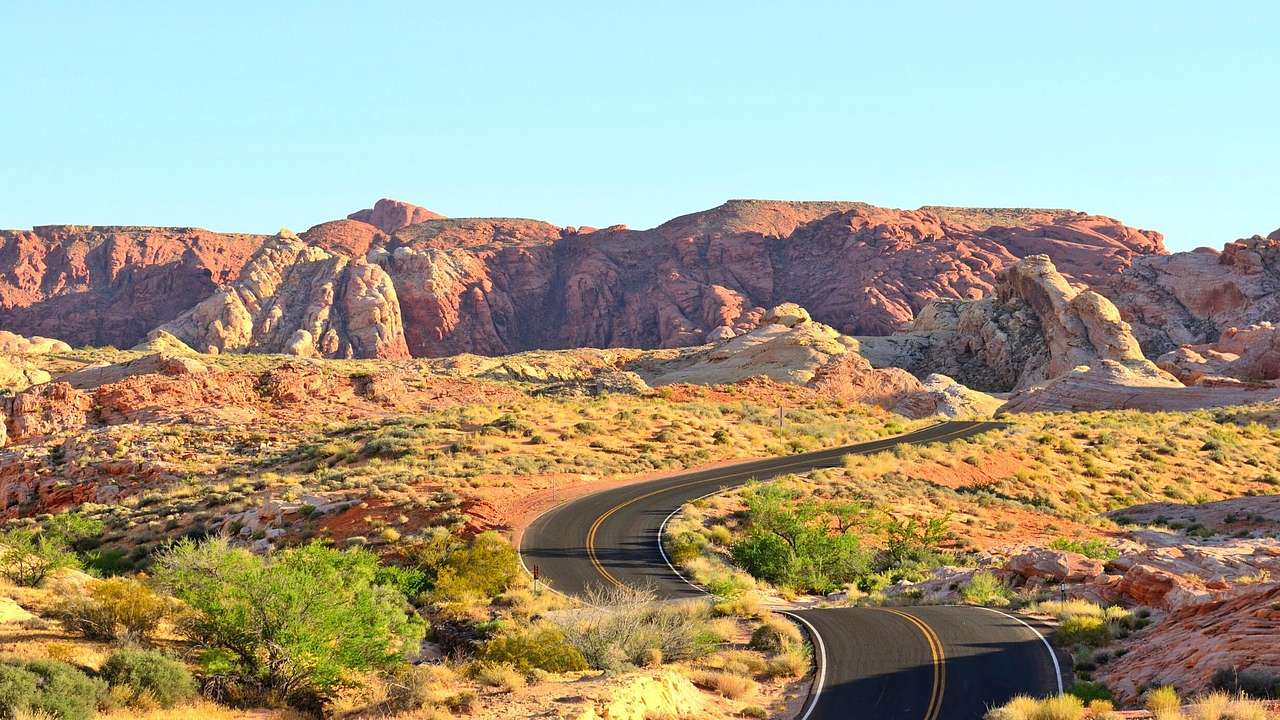 A desert landscape with a road winding toward mountains