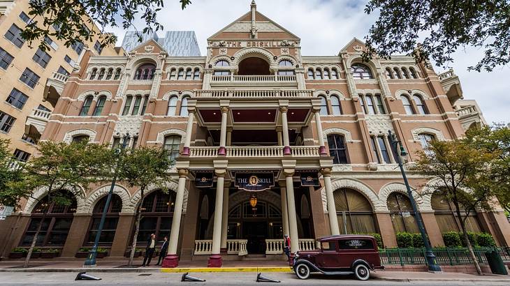 A regal hotel building with an old fashioned car and trees in front of it A regal hotel building with an old fashioned car and trees in front of it