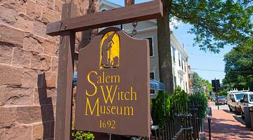 A wooden sign that says "Salem Witch Museum 1692" and has a witch silhouette on it