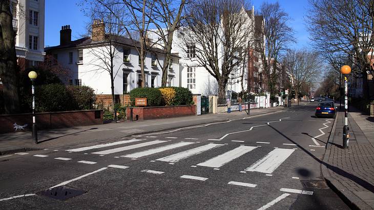 A zebra crossing on the road against some white houses under a blue sky