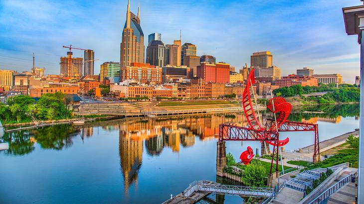 A city skyline reflected on a river in front of it under a blue sky A city skyline reflected on a river in front of it under a blue sky