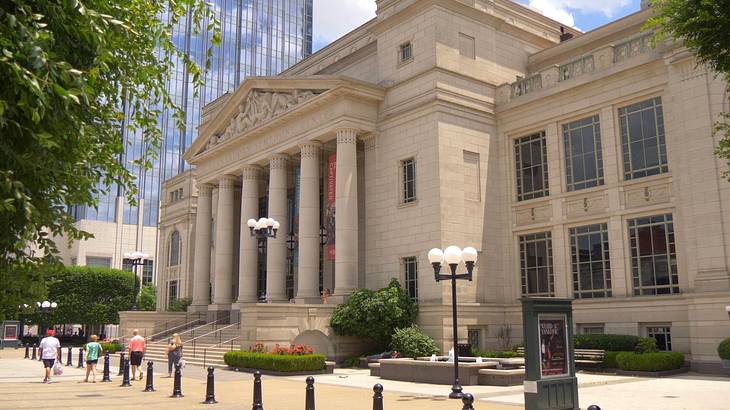 A stone building with columns and a path and trees in front of it A stone building with columns and a path and trees in front of it