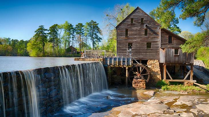A wooden house with a water wheel and a waterfall next to it