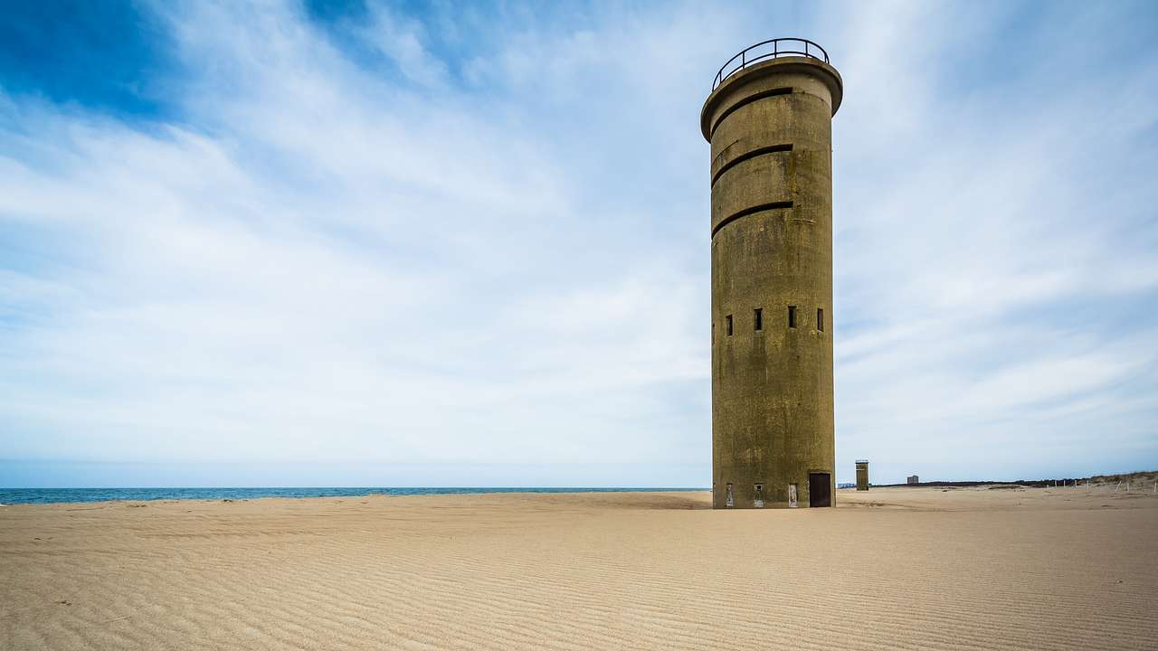 An old observation tower on a beach against a fairly cloudy sky