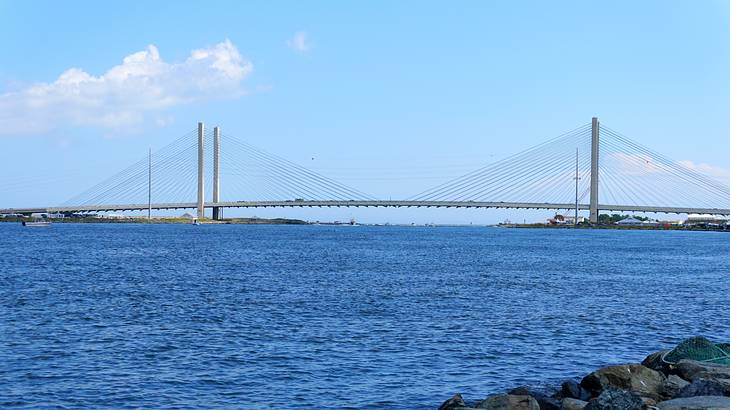 A white cable-stayed bridge over blue waters against a somewhat cloudy sky