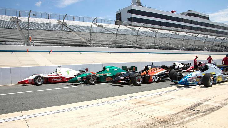 Race cars racing on a pit row in a speedway against empty stands