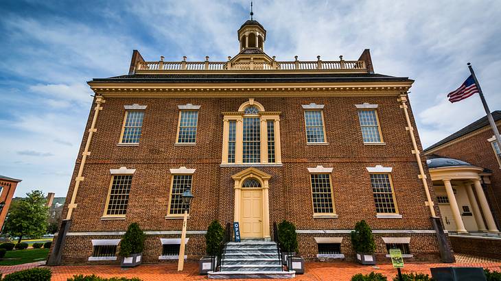 A brown-brick building with an American flag outside under a partly cloudy sky