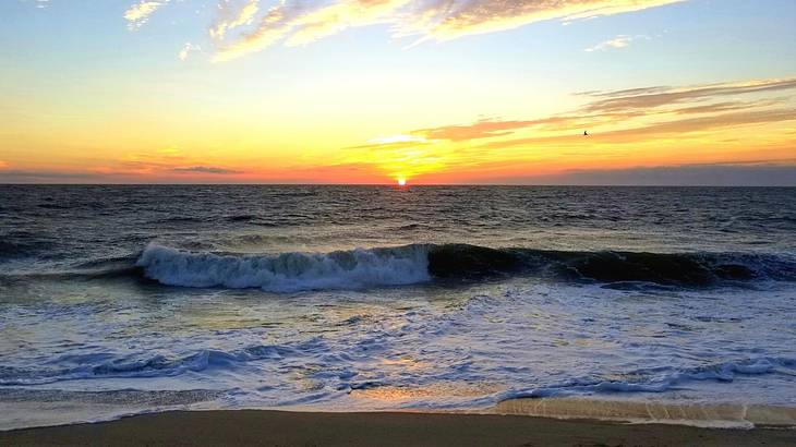 Looking at a sunset over a sea with waves rushing in