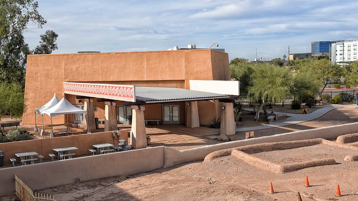 An old brown building with a sunroof outside and white tables and chairs An old brown building with a sunroof outside and white tables and chairs