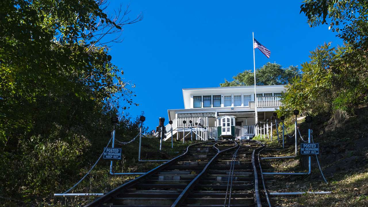 A steep railway leads to a white building with a flag and blue sky above