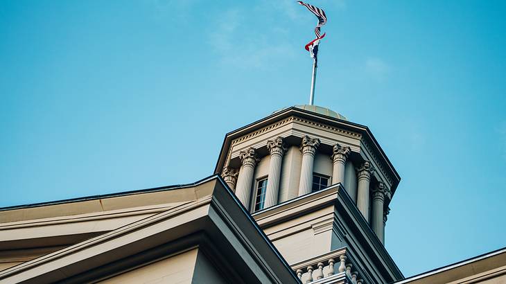 A dome on top of a building with a flag against blue sky