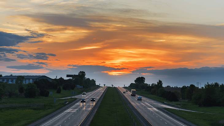 Two highway lanes alongside each other with greenery around, during a sunset