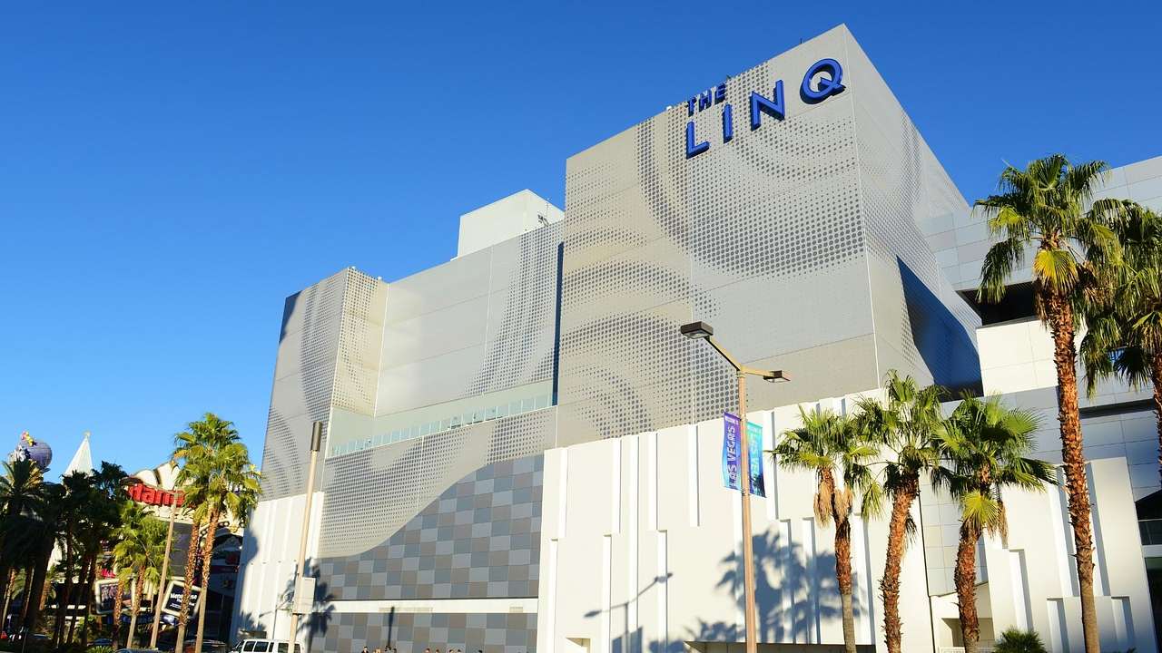 A contemporary hotel building with LINQ sign and palm trees in front of it
