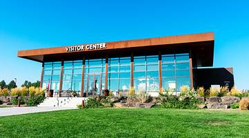 A modern building with a "Visitor Center" sign and grass in front of it