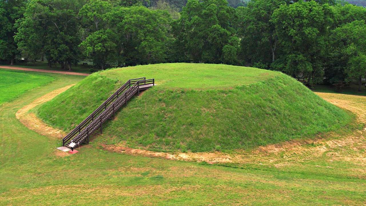 A small mound covered with green grass and a staircase leading to the top