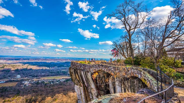 A pathway to a mountain's rocky edge with a lookout surrounded by trees