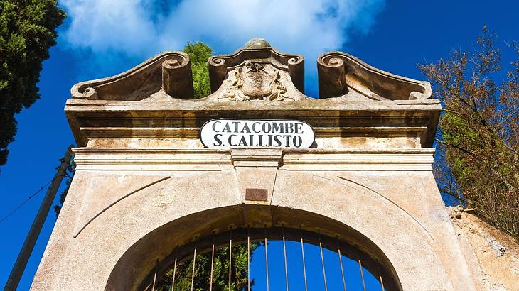 An arched gate with a sign that says "Catacombe S. Callisto"
