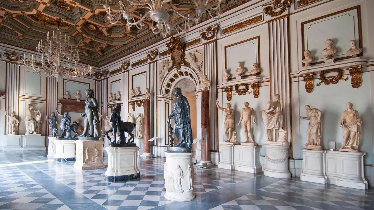 A museum with ancient statues on display and a black and white marble floor