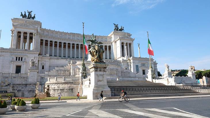 A large stone monument with statues and Italian flags on it and steps in front of it