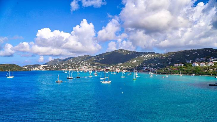 A bay with boats in it and mountains behind under a blue sky with clouds