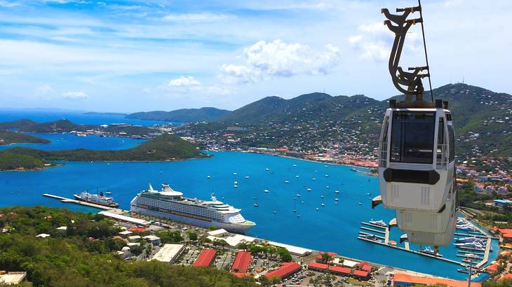 A gondola system with a view of a harbor, boats, and greenery below