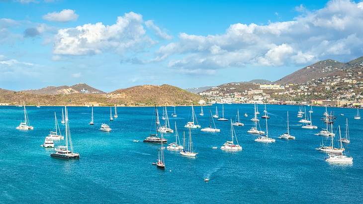 Boats in a bay with mountains in the background under a blue sky with clouds