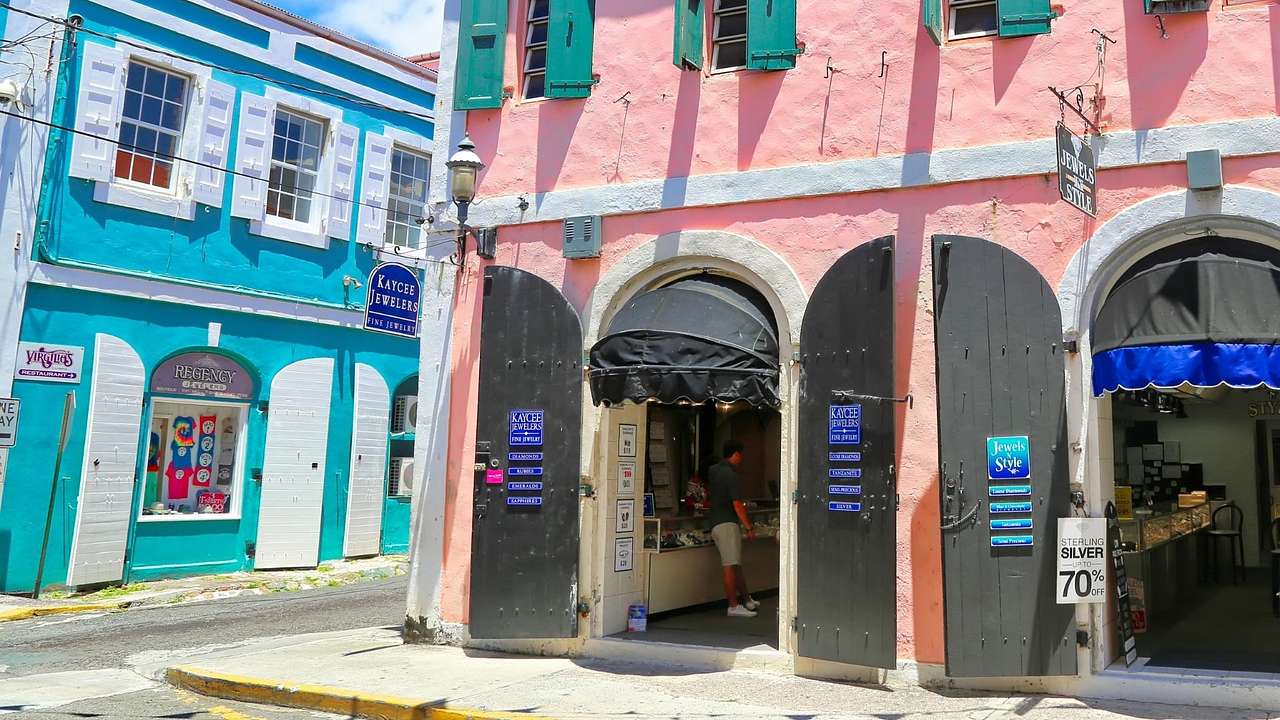 Blue and pink buildings with window and door shutters on a street