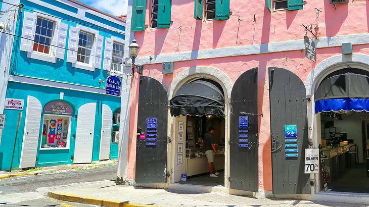 Blue and pink buildings with window and door shutters on a street