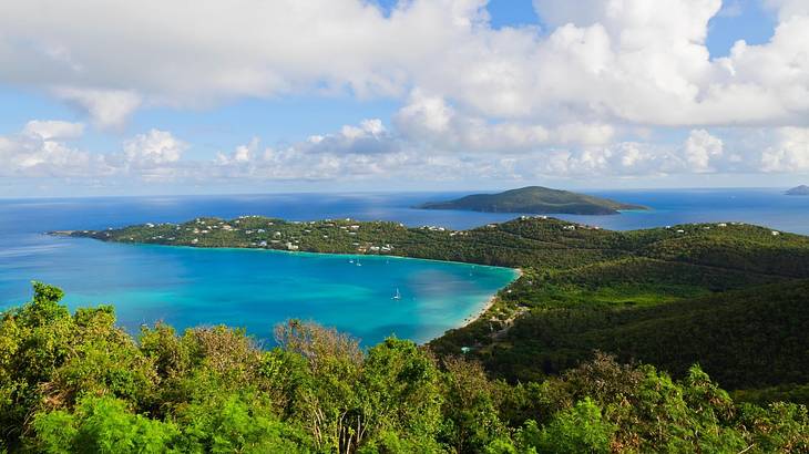 Greenery-covered mountains stretching out into the sea under a cloudy sky