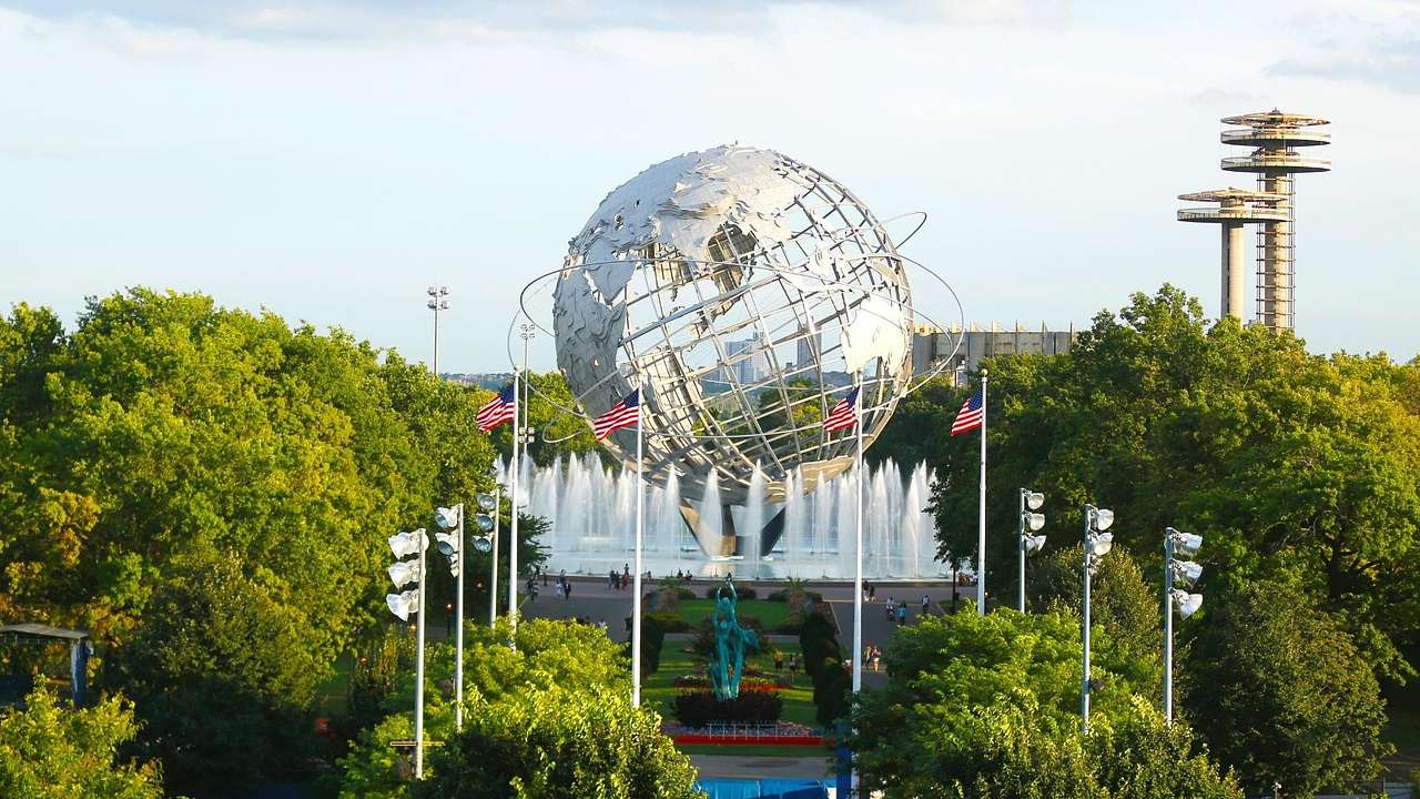 A globe structure with US flags, water fountains, and trees around it
