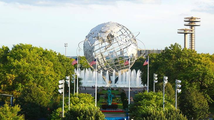 A globe structure with US flags, water fountains, and trees around it