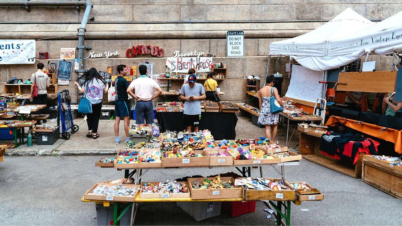 An outdoor flea market with stalls and people shopping