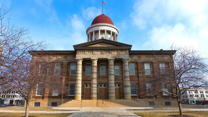 A walkway to a neoclassical building with a red dome against a partly cloudy sky A walkway to a neoclassical building with a red dome against a partly cloudy sky