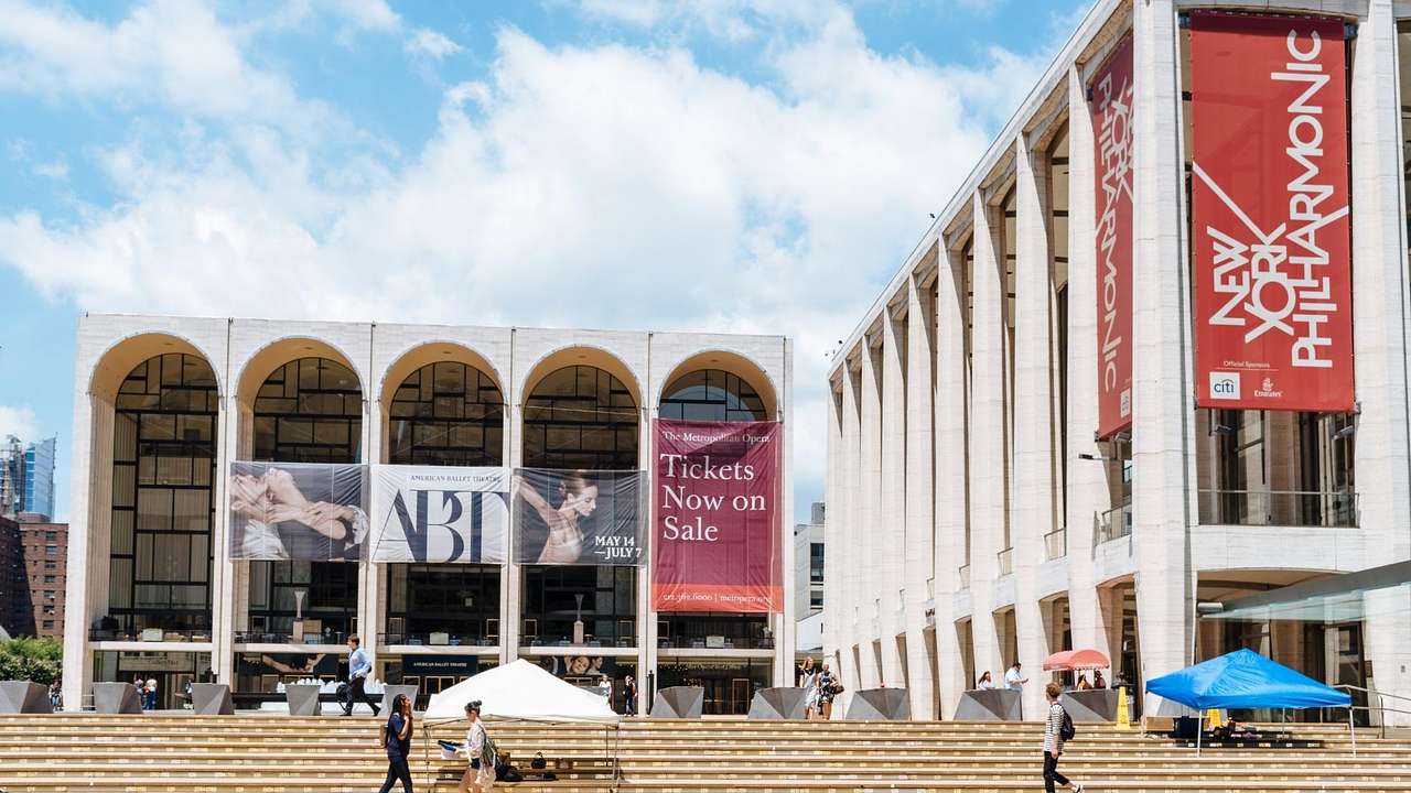 Two buildings in a square with signs for the New York City Ballet and Philharmonic