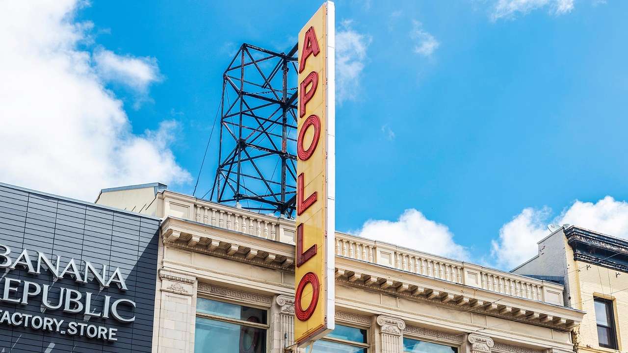 A sign that says 'Apollo" on a building under a bright blue sky with white clouds