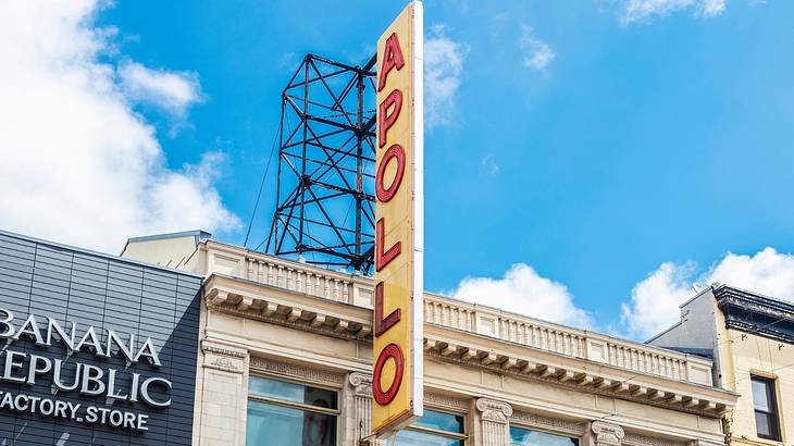 A sign that says 'Apollo" on a building under a bright blue sky with white clouds