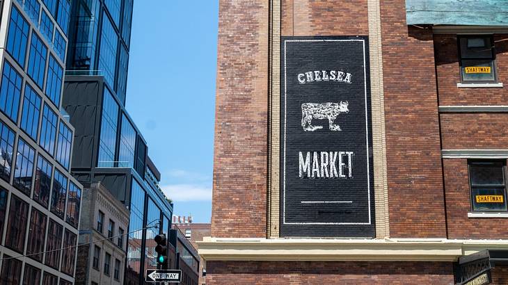 A brick building with a black and white Chelsea Market sign with a cow on it