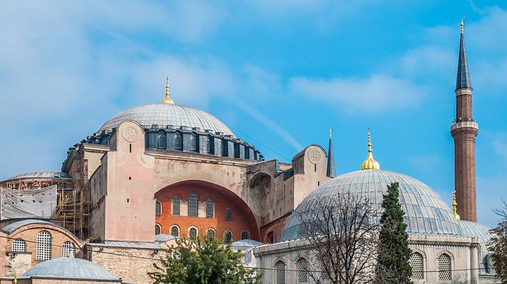 An old mosque building with two blue domes and a huge arched door