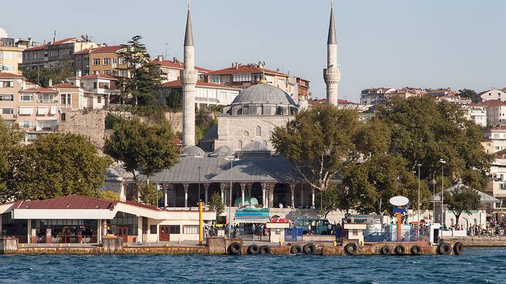 A pier overlooking blue water with a mosque at back