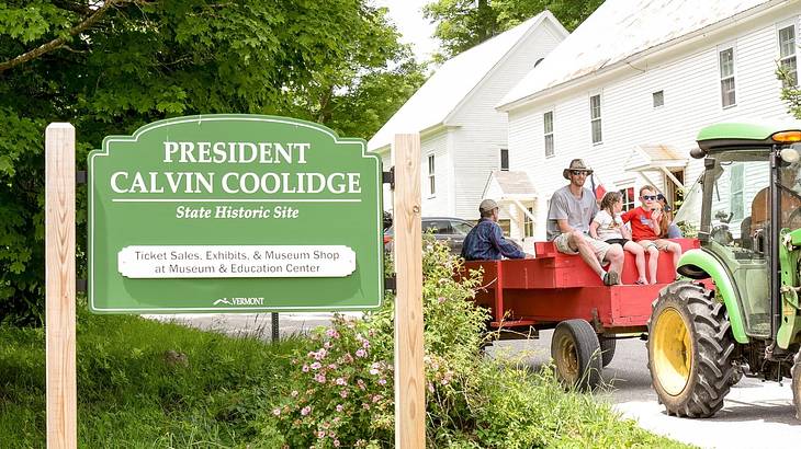 A green "President Calvin Coolidge State Historic Site" sign next to a tractor