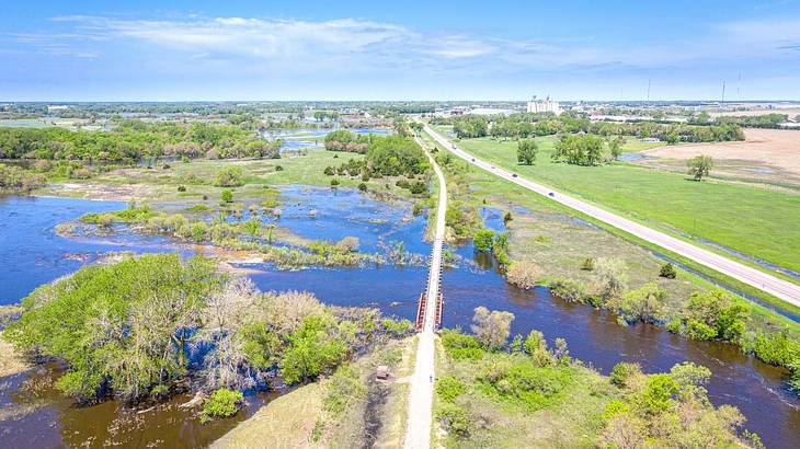 An aerial of a trail and a road going through a river and grassland