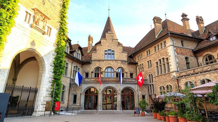 An ancient stone building with a conical roof and swiss flags outside